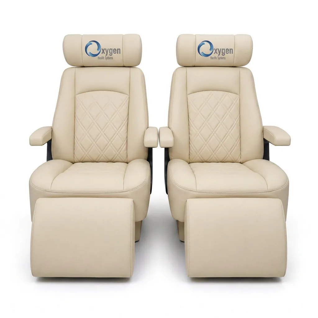 Pair of cream quilted-leather reclining captain's chairs with embroidered Oxygen Health Systems headrests, padded armrests, and extended footrests