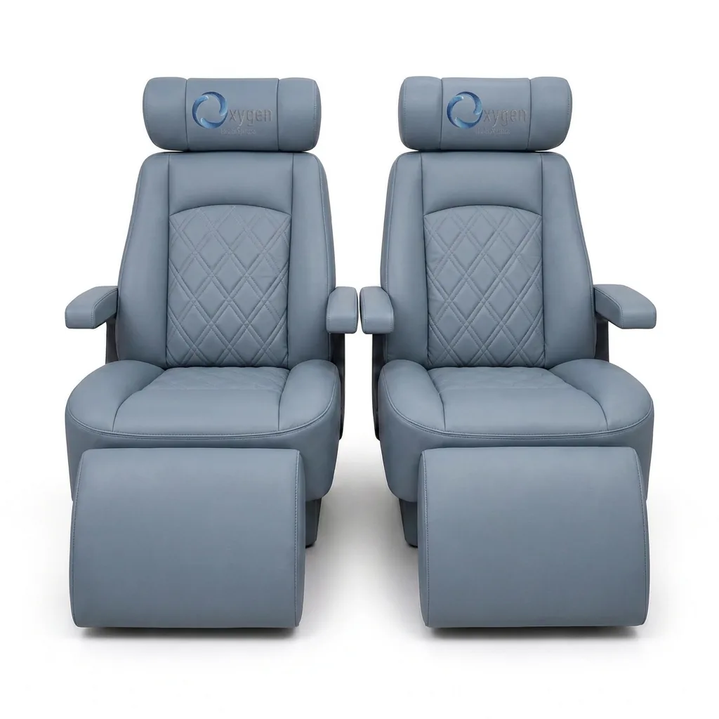Pair of powder gray quilted-leather reclining captain's chairs with embroidered Oxygen Health Systems headrests, padded armrests, and extended footrests